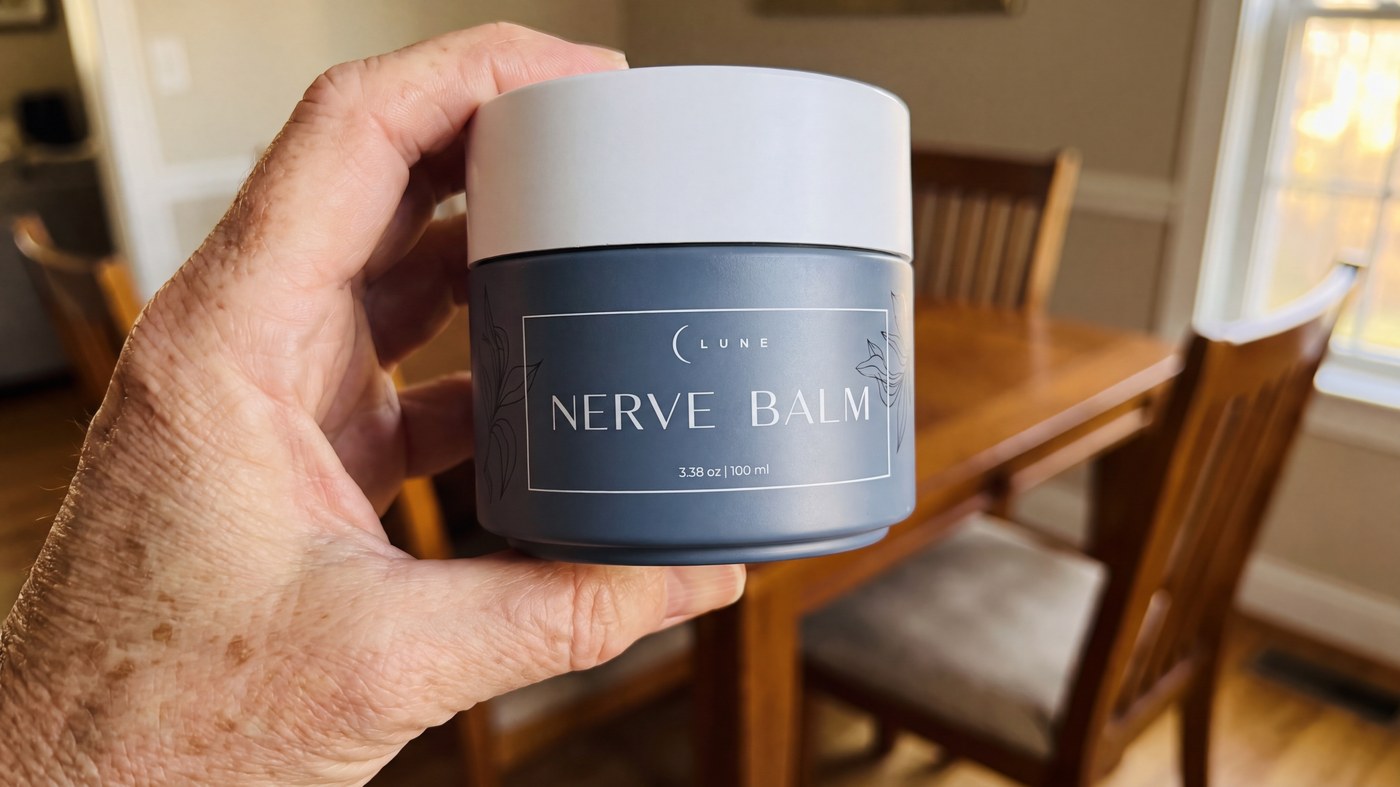 An older person holding a jar of Lune Nerve Balm in a sunlit dining room