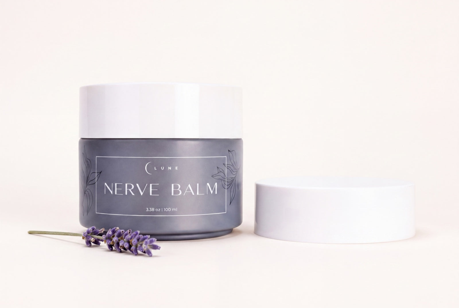 A jar of Lune Nerve Balm on a bedside table beside a framed photograph and reading glasses.
